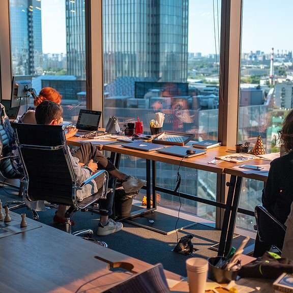 a group of people sitting at a table with laptops